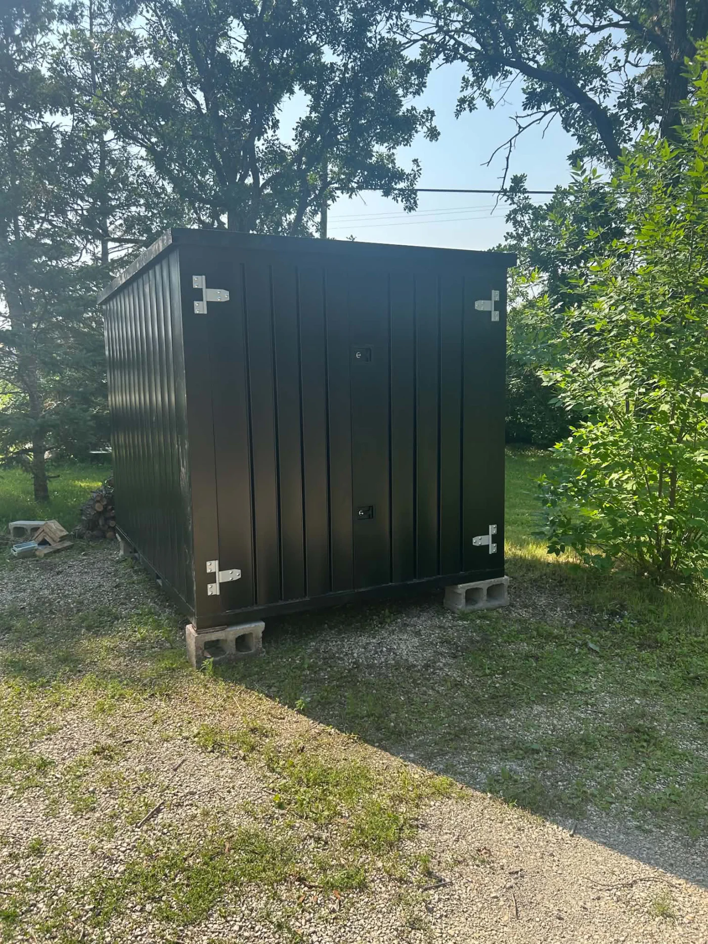 Completed black powder-coated flat-pack steel storage container installed outdoors