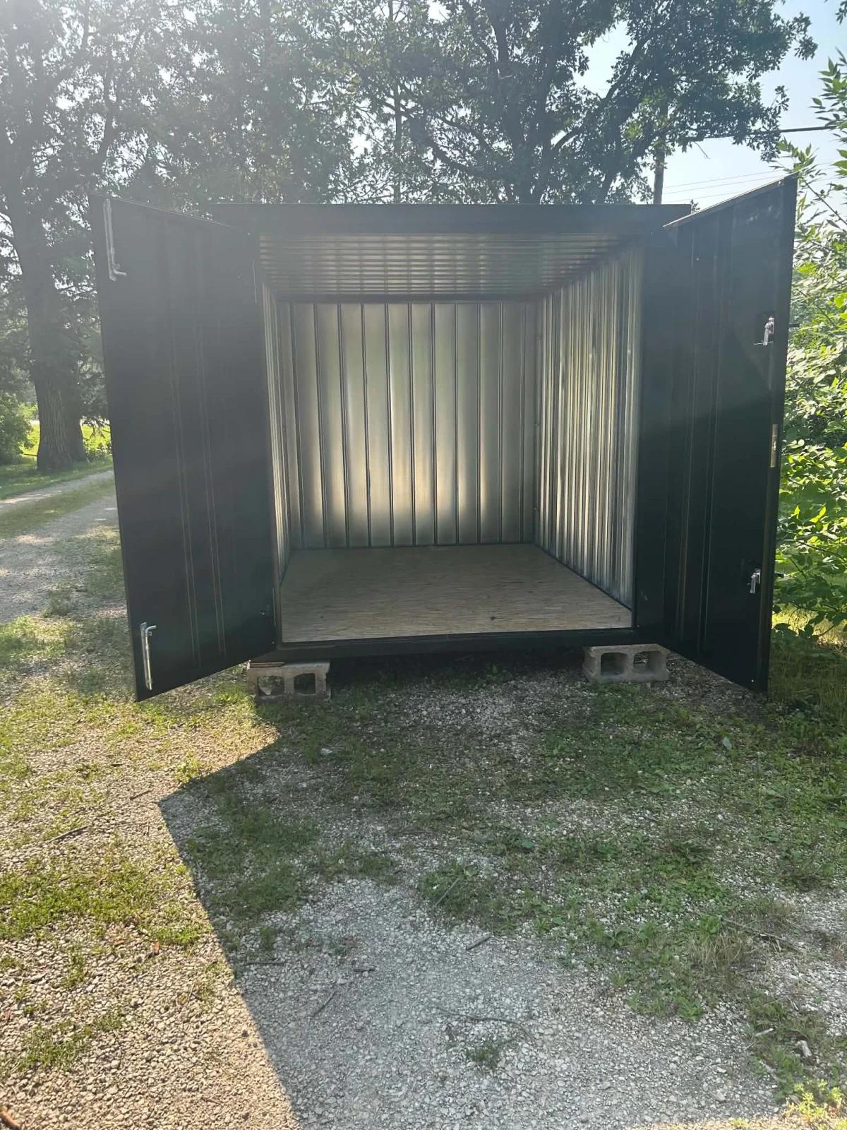 Open 7 by 13 foot flat-pack storage container showing its galvanized interior and plywood floor