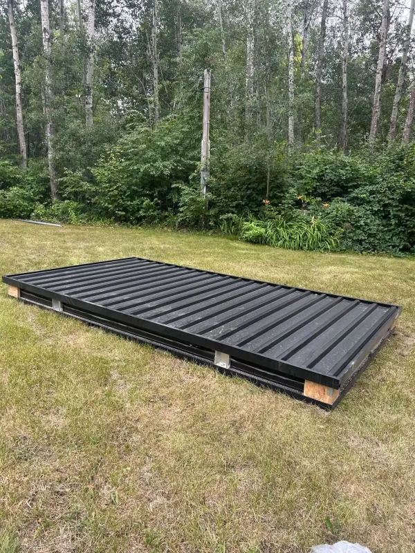 Flat-pack storage container components stacked flat on a lawn for delivery